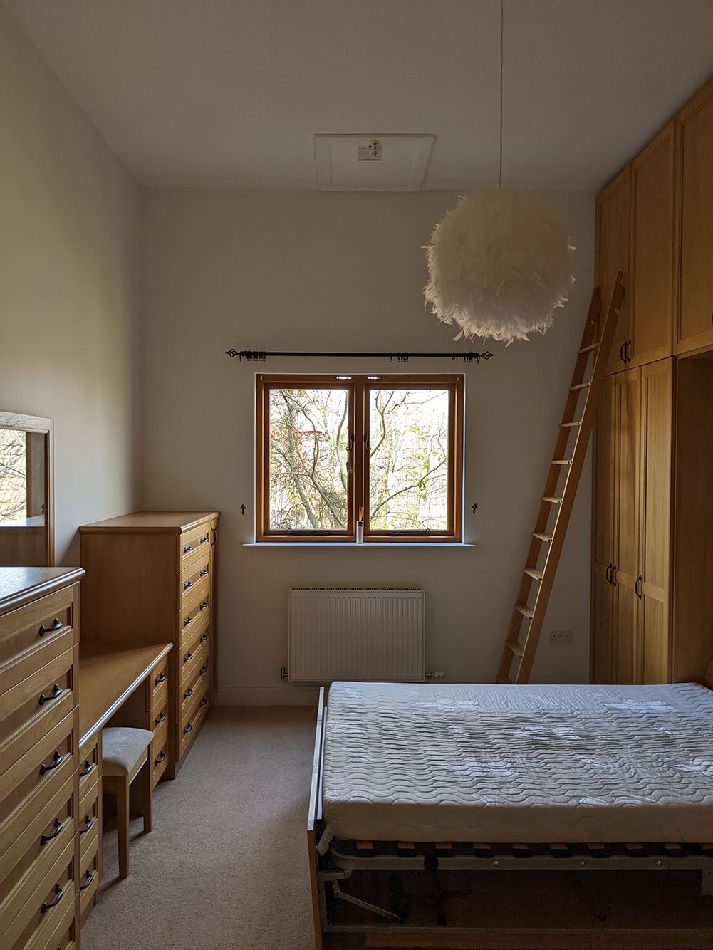 A before photo of the sewing room showing beige walls and a fluffy light fitting.