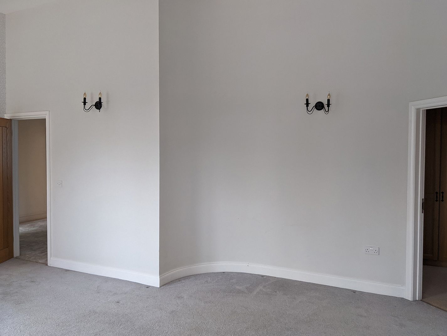 A before photo of thee bedroom showing the grey walls and black wall lights.