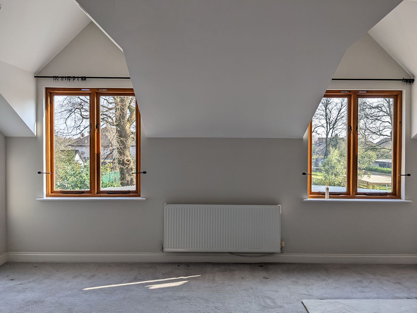 A before photo of the main bedroom which has grey walls and carpet and a radiator where the bed will go.