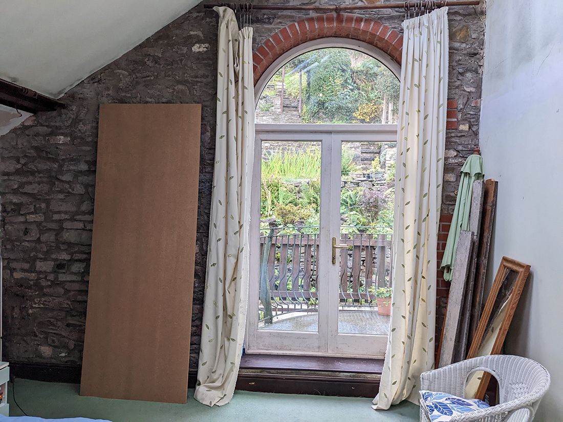 A before photo showing the blank wall where the wardrobes now are, and the French doors with the old curtains.