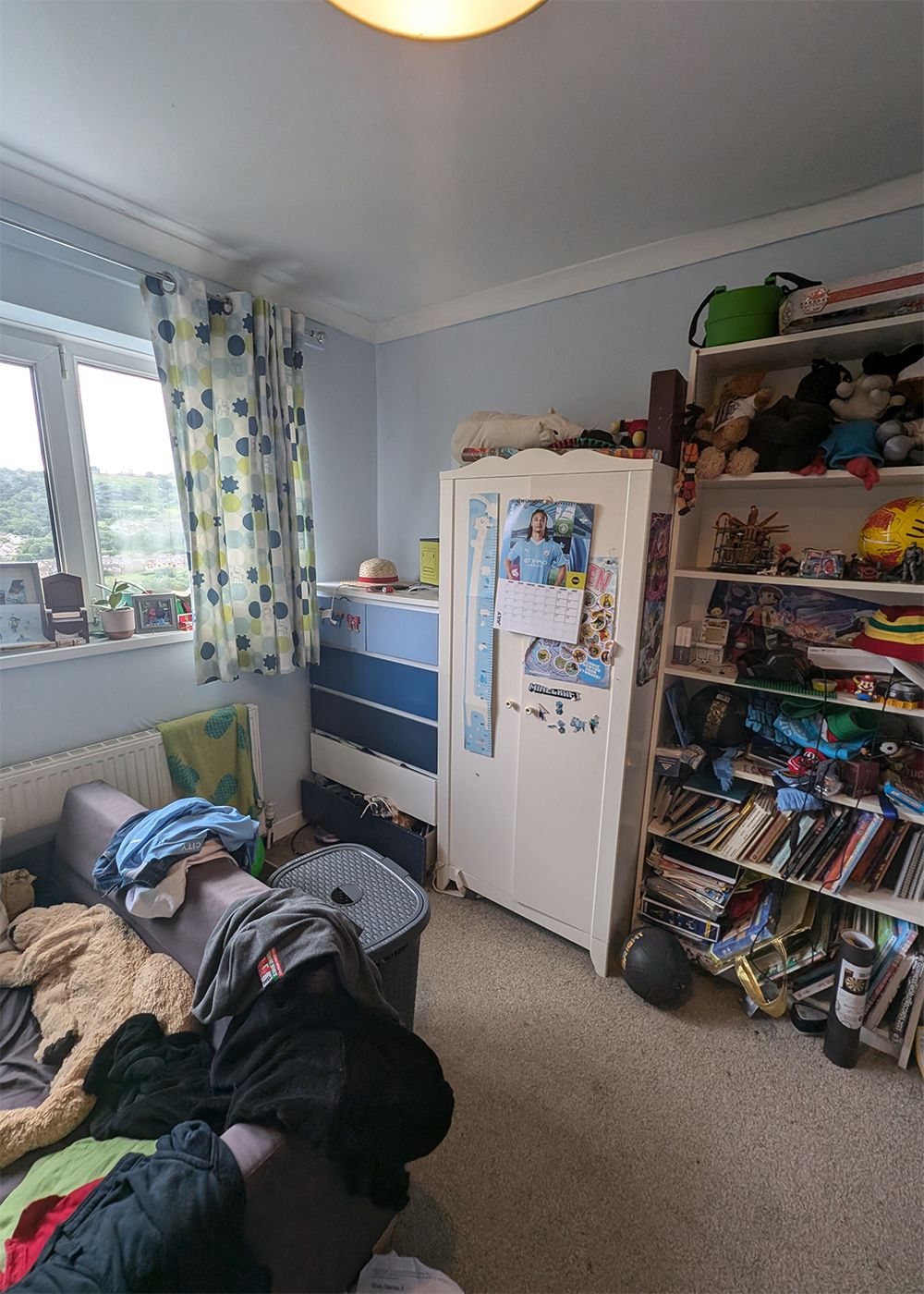 The same corner with a child's wardrobe and overfull shelving in white.
