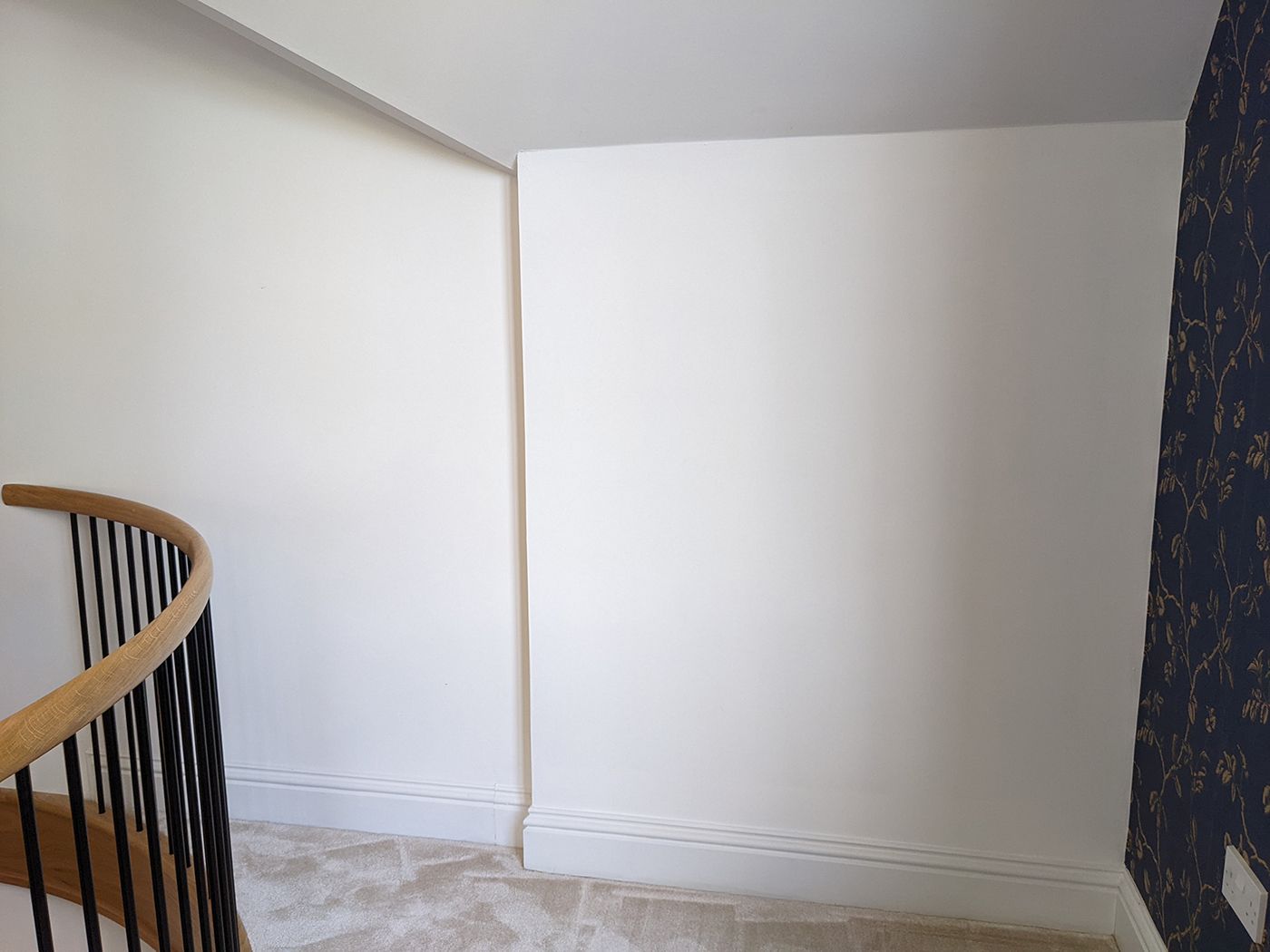A before image of the mezzanine reading nook with white walls and a dark blue feature wall.