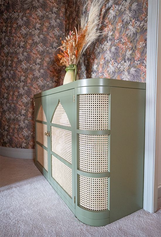 A side view of the bespoke linen cupboard which is finished in sage green and rattan.